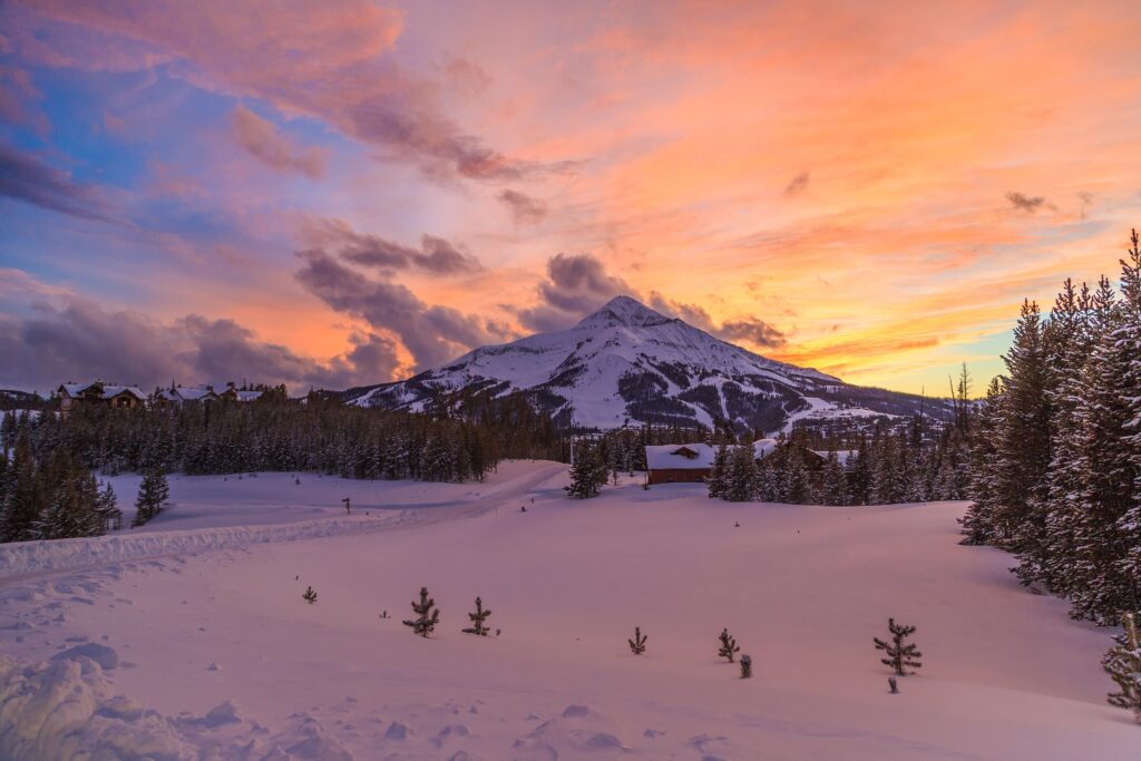 Lone Mountain under a pink and orange sunset above snowy meadows in Big Sky, Montana